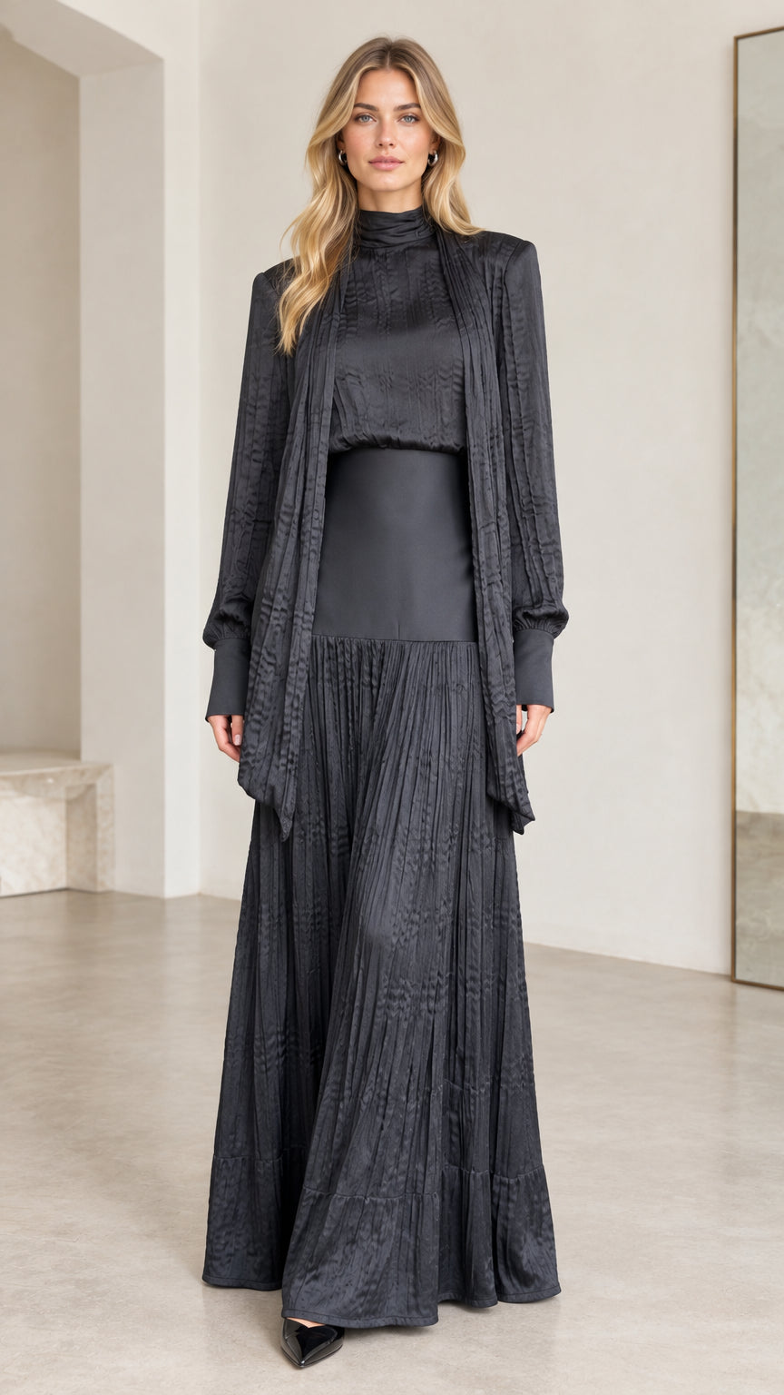 Front full-length view of woman wearing black textured pleated maxi dress set with cardigan