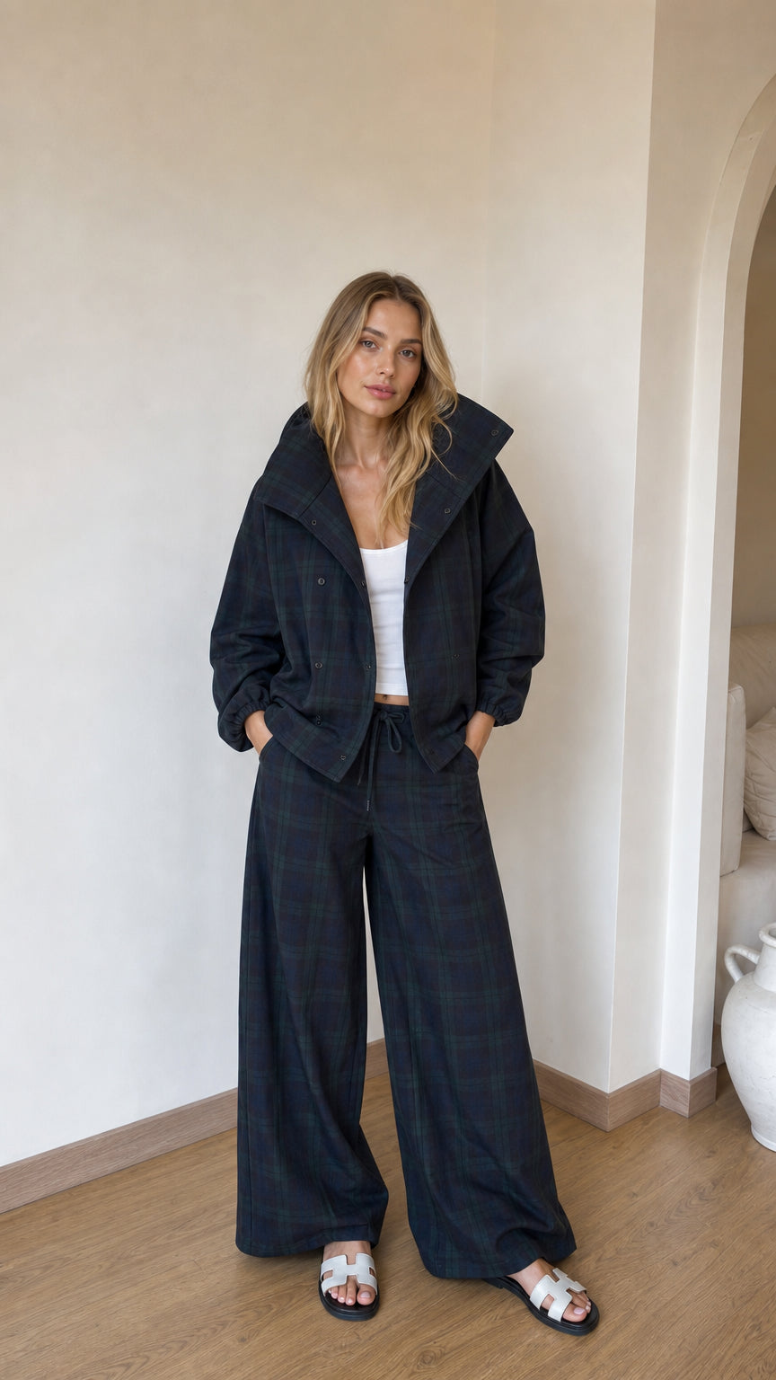Model wearing black plaid high-collar jacket and matching wide-leg trousers front view