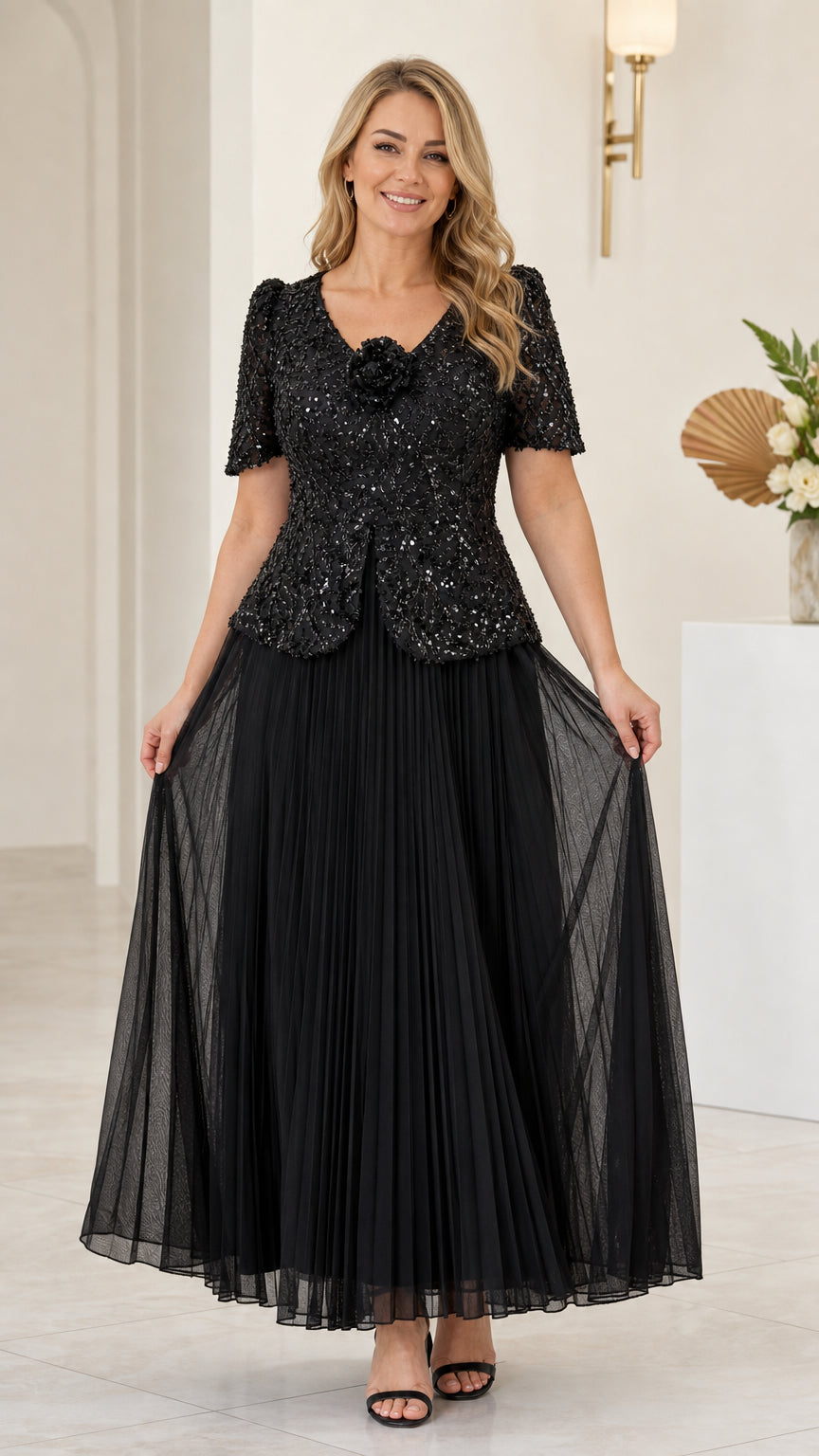 Front full view of woman wearing black sequin V-neck maxi dress with pleated skirt