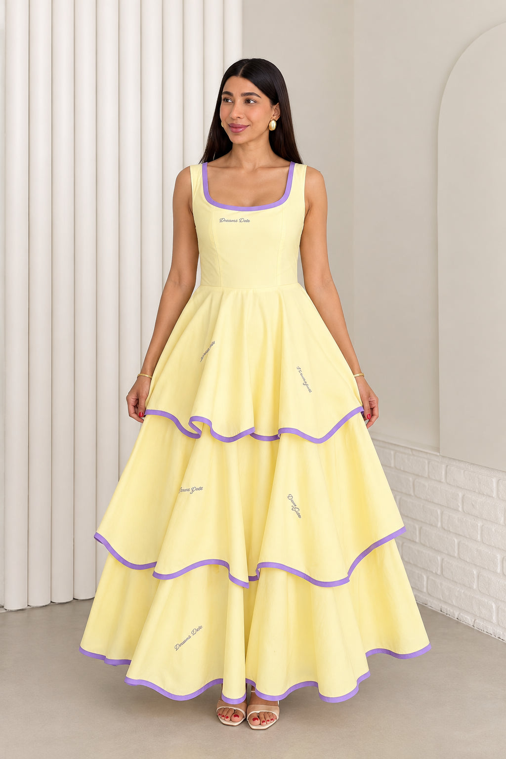 Model wearing pastel yellow sleeveless tiered maxi dress with purple contrast trim, front view