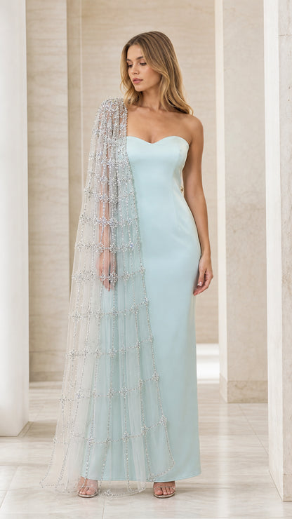 Front view of model wearing ice blue strapless evening gown with attached sheer beaded cape