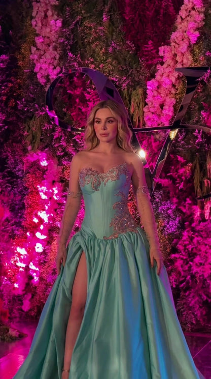 Front view of woman wearing turquoise strapless corset evening gown with high slit and embroidery