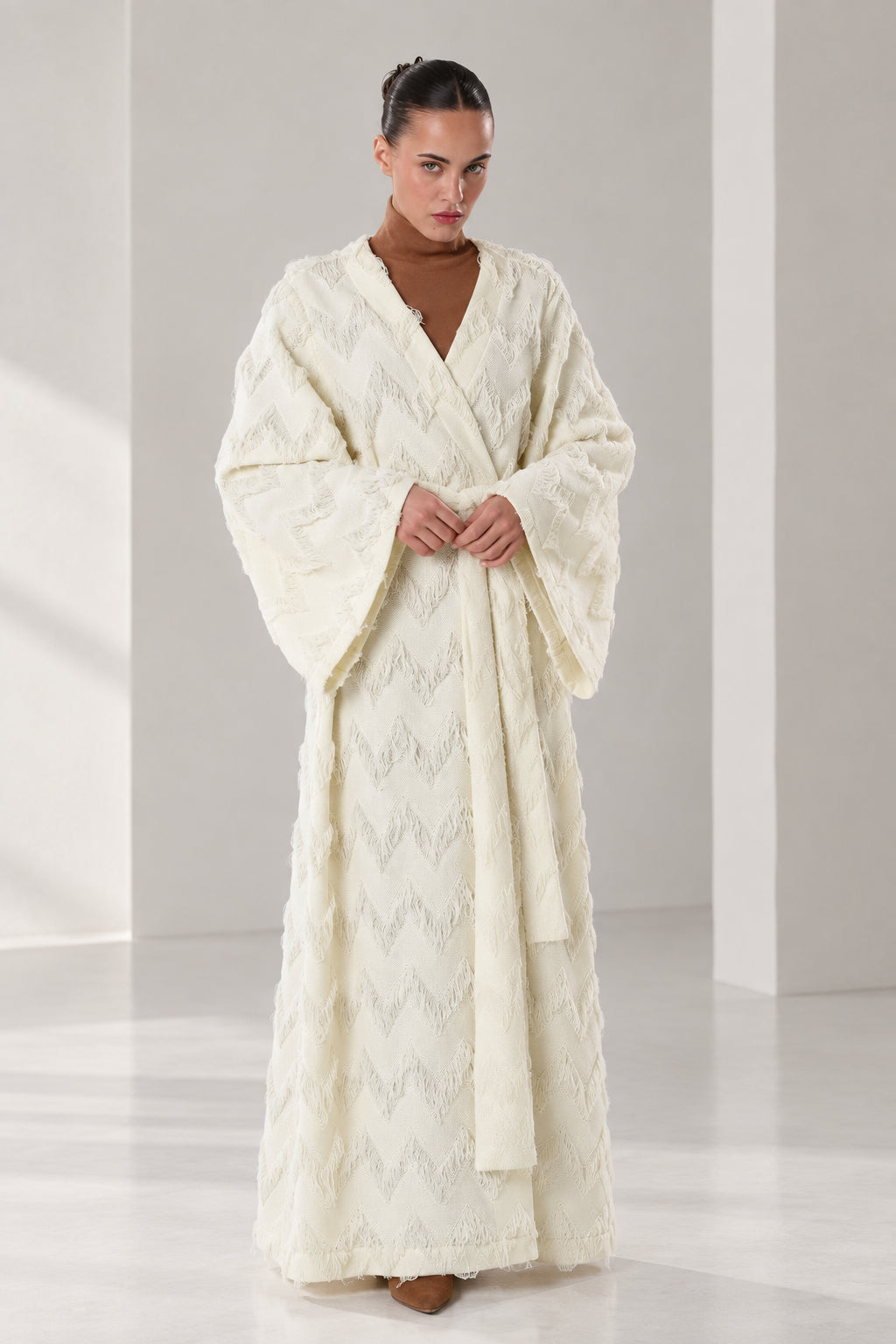 Front full view of woman wearing cream textured chevron fringe wrap maxi robe with waist belt
