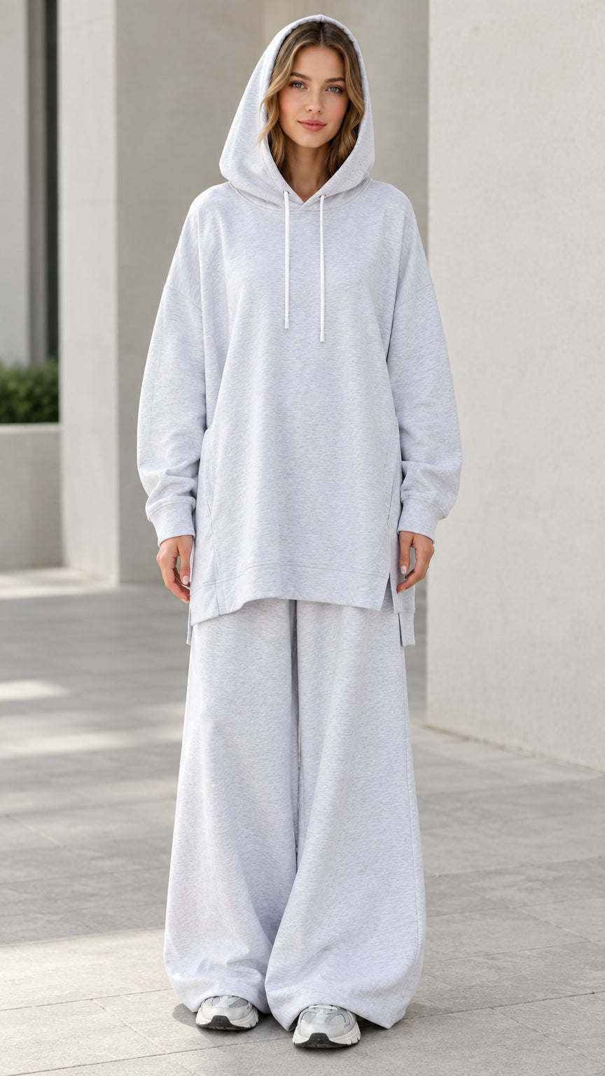 Front view of woman wearing oversized light heather grey tunic hoodie and matching wide-leg sweatpants