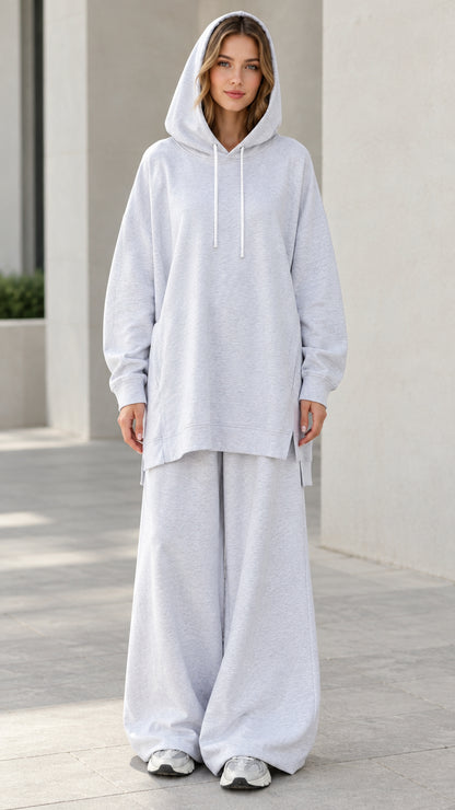 Front view of woman wearing oversized light heather grey tunic hoodie and matching wide-leg sweatpants