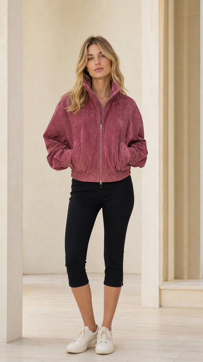 Front view of woman wearing rose pink full-zip bomber jacket with black capris and sneakers