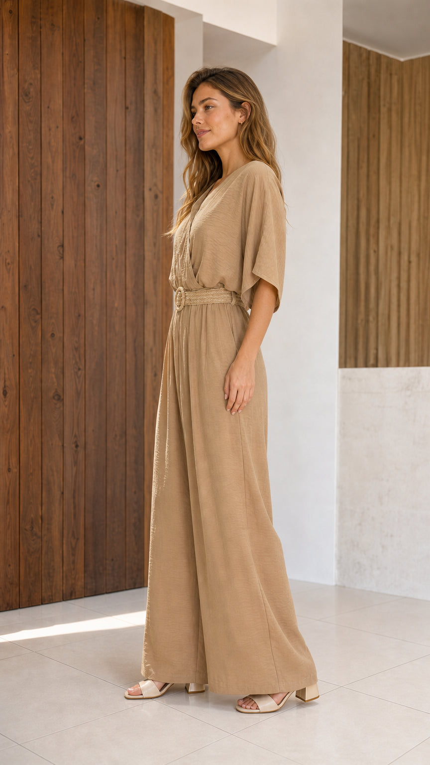 Side profile of woman in beige wide-leg jumpsuit with woven belt