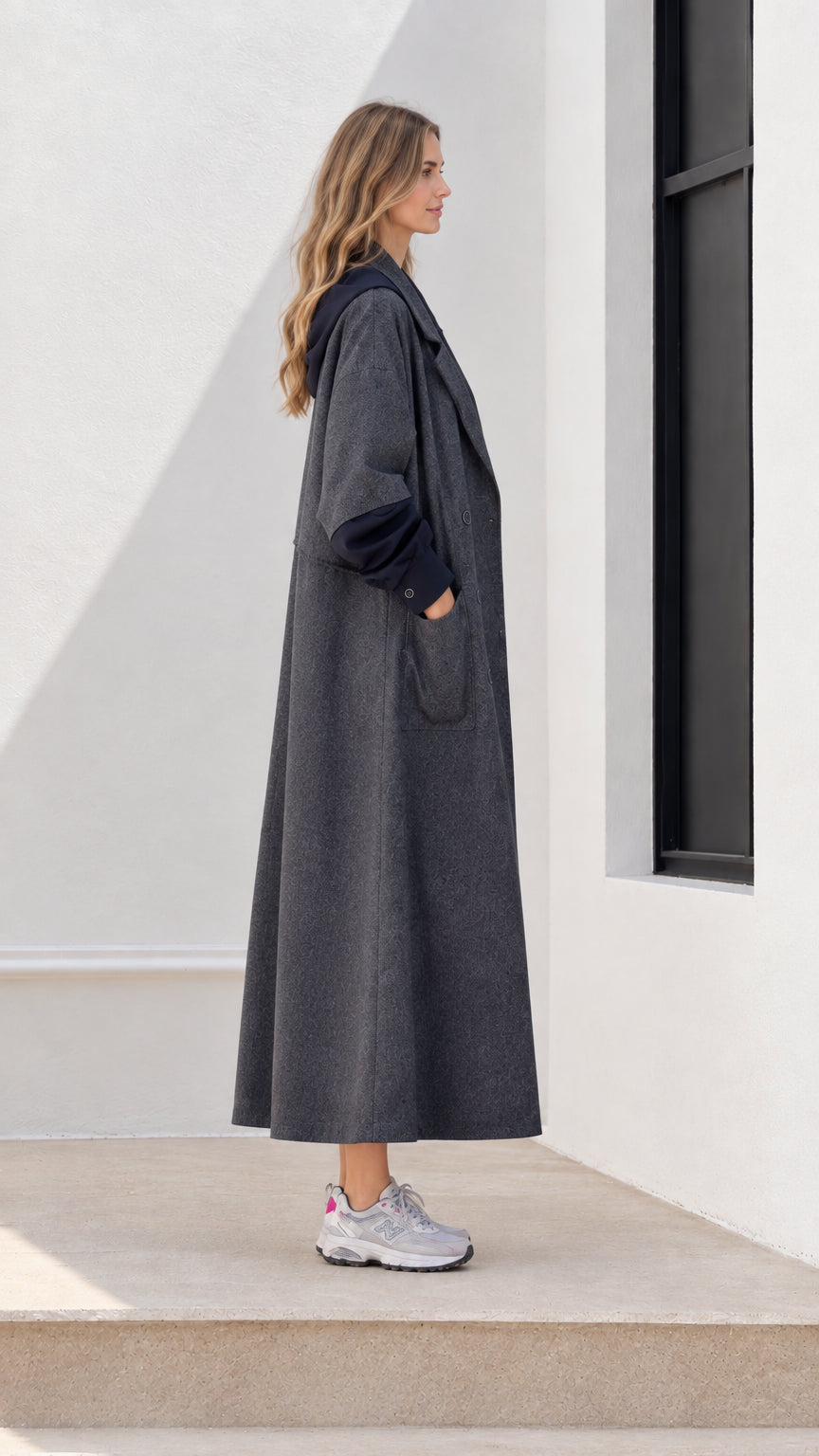 Side profile of woman in long charcoal grey double-breasted coat