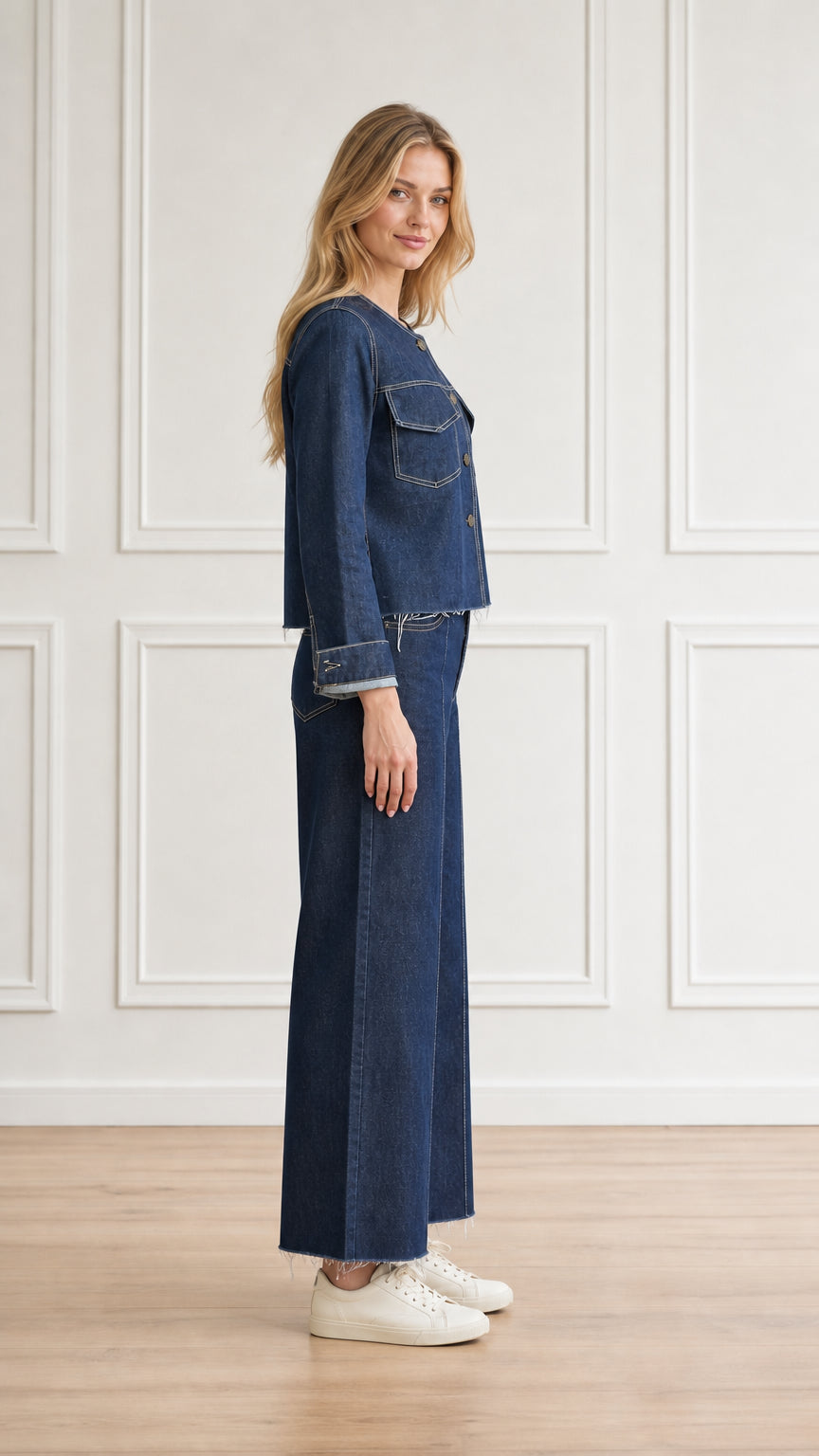 Side profile view of model wearing dark blue collarless denim co-ord set with white sneakers