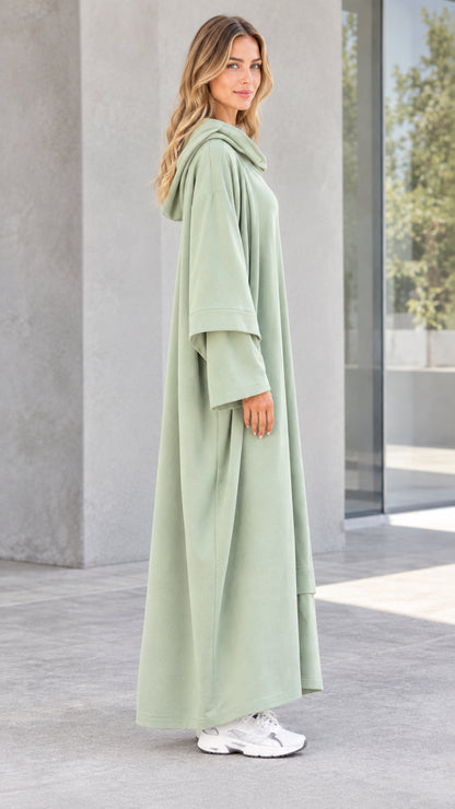 Side profile view of woman wearing long sleeve sage green hooded maxi dress