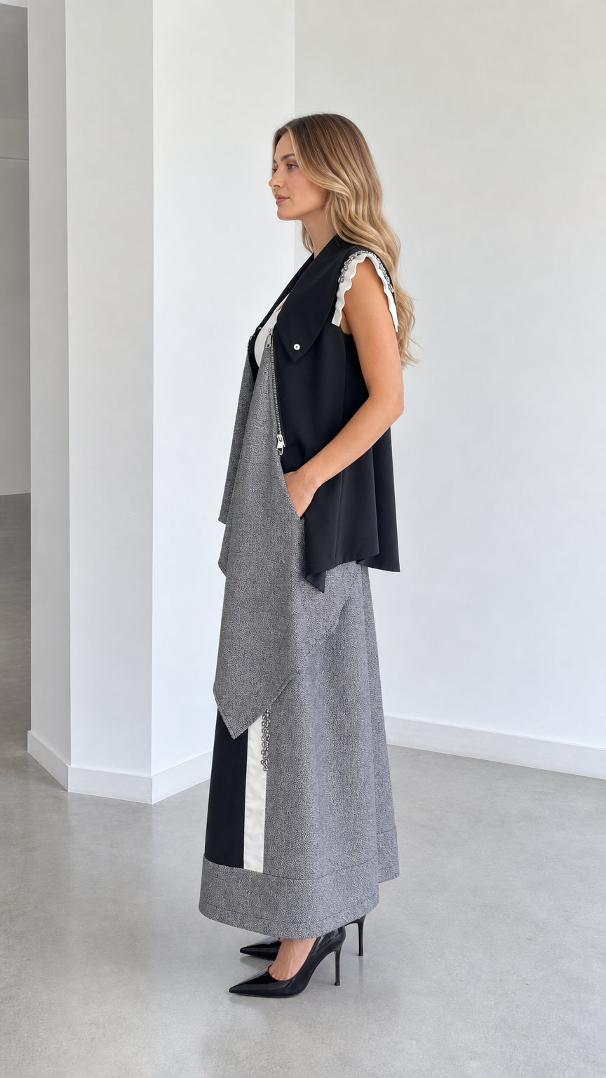 Side view of model wearing black and grey draped gilet and wide-leg trousers set