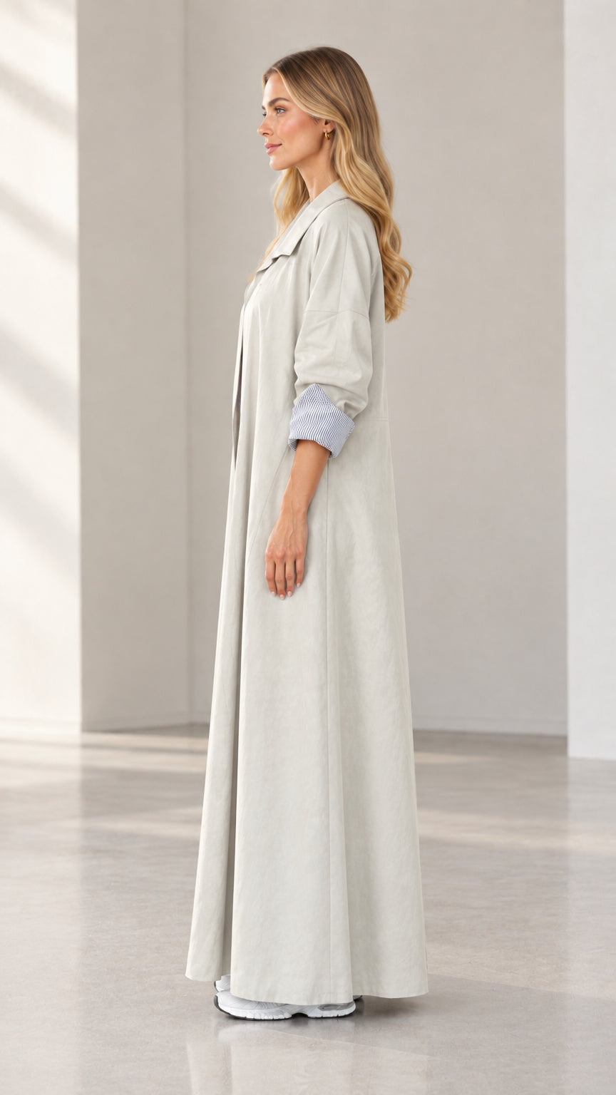 Side profile view of woman modeling light grey floor-length duster trench coat