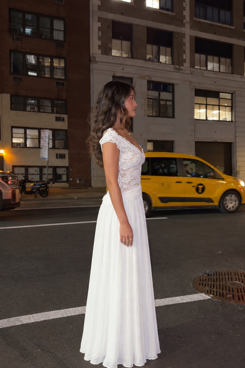 Side view of woman in floor-length white lace formal evening dress