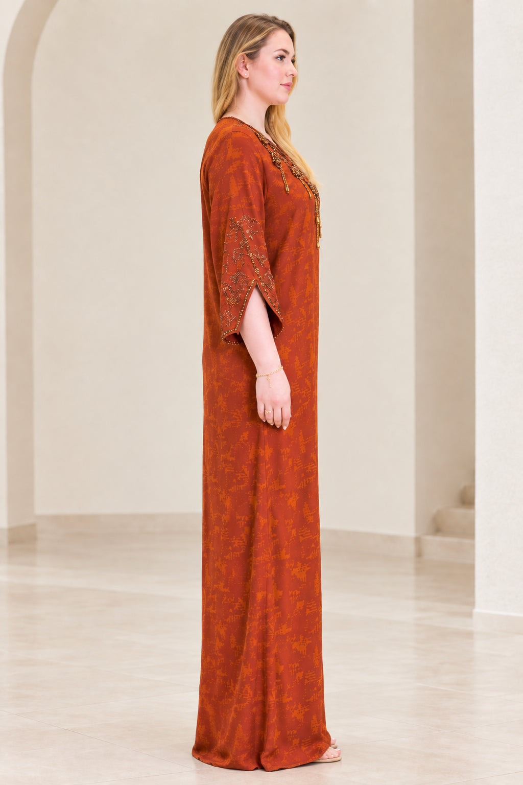 Side profile view of woman wearing rust orange full-length caftan dress