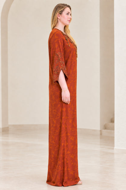 Side profile view of woman wearing rust orange full-length caftan dress
