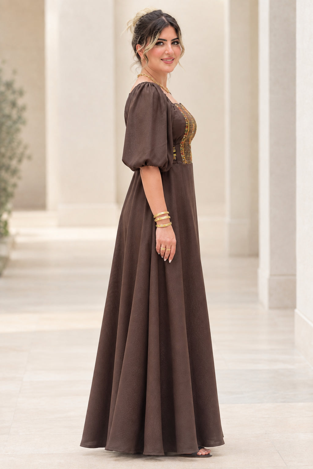 Side profile view of woman wearing brown A-line maxi dress with puff sleeves