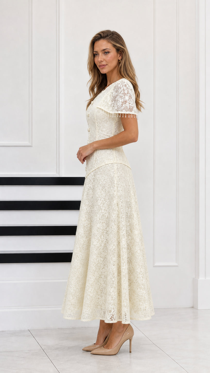 Side profile of woman wearing cream lace evening gown with capelet detail