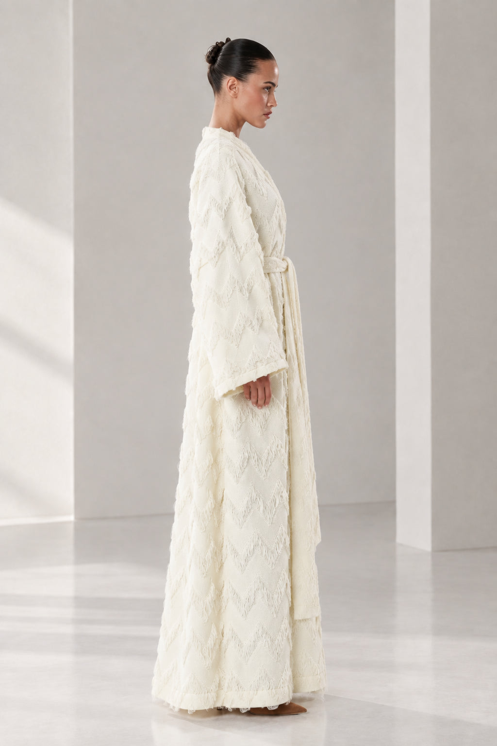 Side angle view of woman in cream textured maxi wrap robe showcasing full length fit