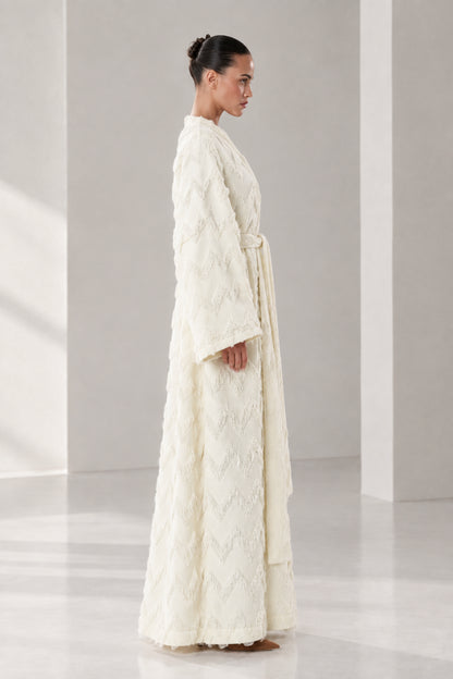Side angle view of woman in cream textured maxi wrap robe showcasing full length fit