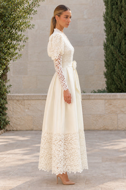 Side profile of woman wearing ivory lace and satin maxi dress with tie belt