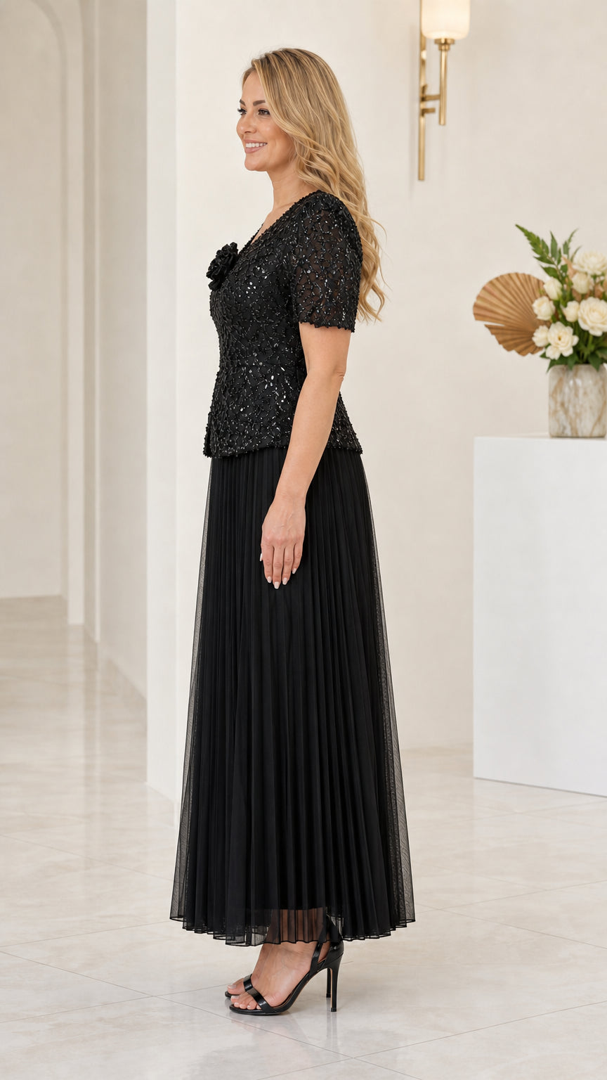 Side profile view of elegant black sequin short sleeve pleated evening gown