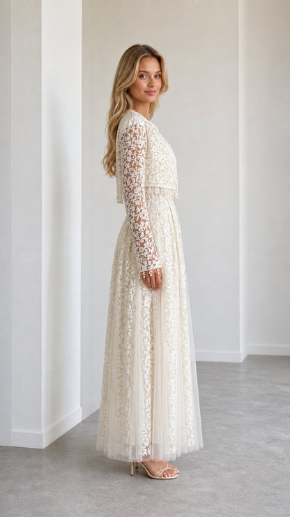 Side profile of model in ivory lace evening gown and long sleeve jacket
