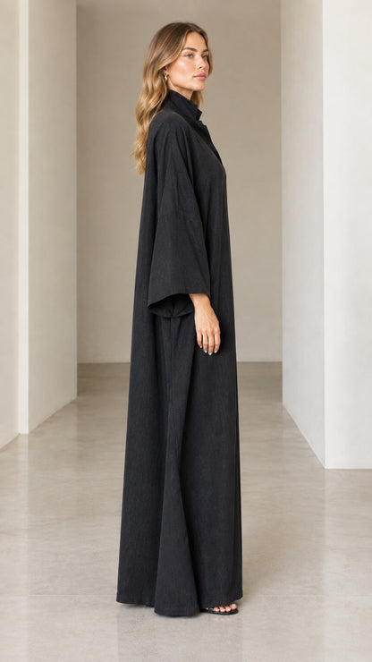 Side view of woman wearing flowing black full-length kaftan with wide sleeves