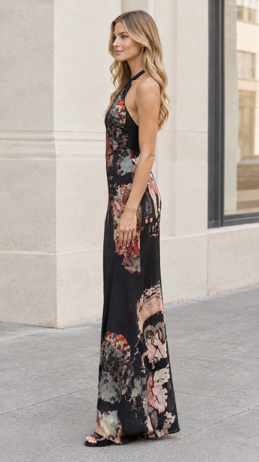 Side view of model in black floral print sleeveless halter maxi dress
