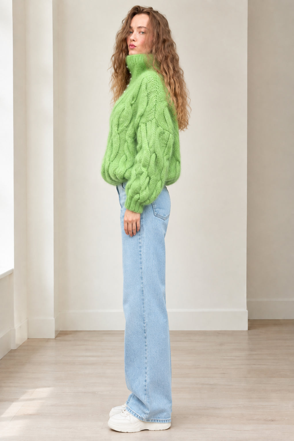 Side profile view of model wearing lime green cable knit sweater