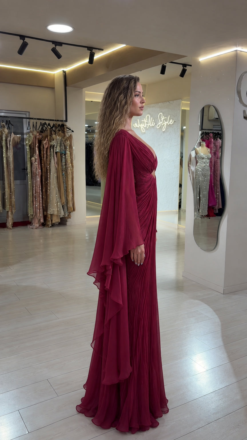 Side profile view of burgundy pleated cape sleeve evening maxi dress