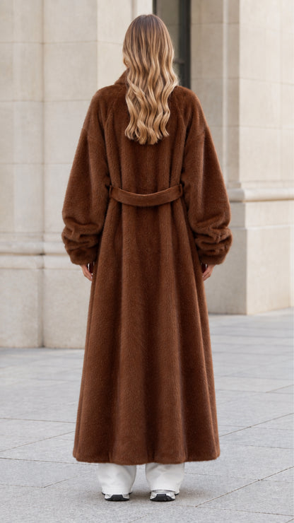 Back view of woman wearing chocolate brown plush coat highlighting the back belt detail