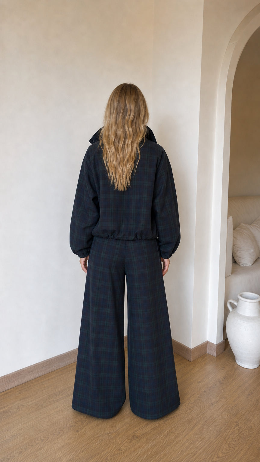 Back view of model wearing dark plaid jacket and relaxed wide-leg pants