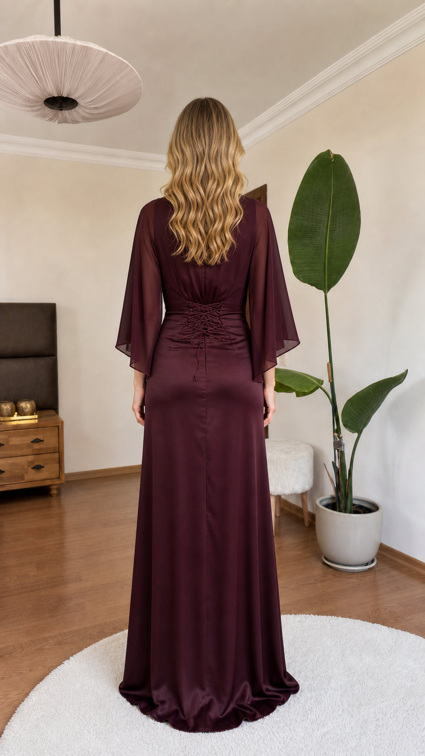 Back view of model in burgundy satin dress showing draped cape and floor-length skirt