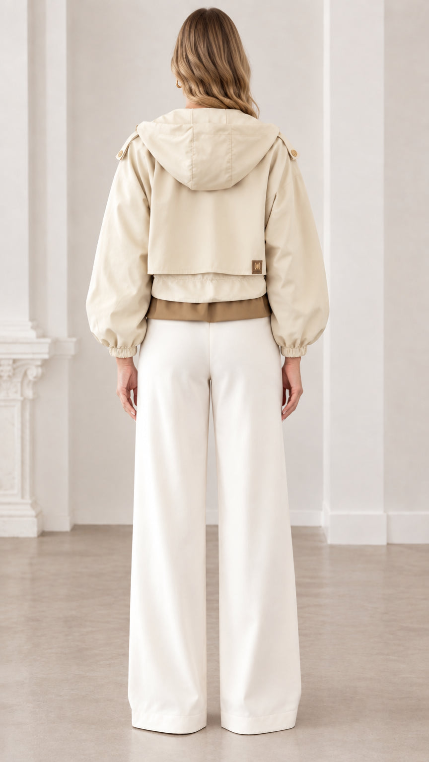 Back view of woman showing the hood and hem design of beige cropped utility jacket