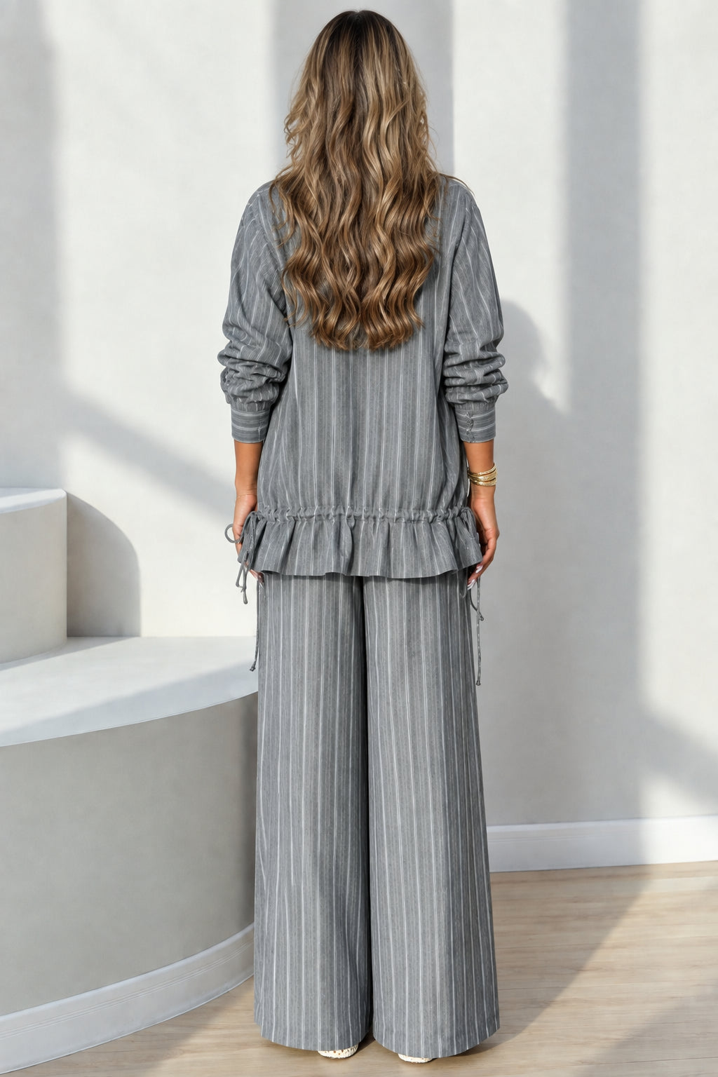 Back full-length view showing the ruffled drawstring hem of the grey pinstripe jacket set