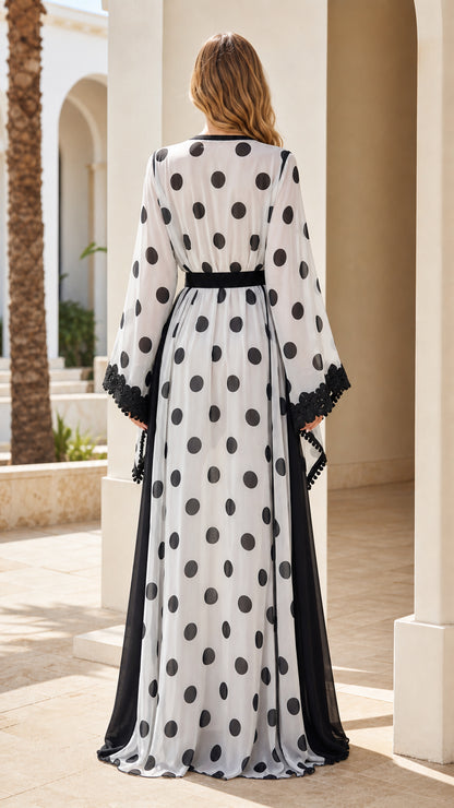 Back view of woman wearing floor-length white polka dot kaftan dress with belted waist