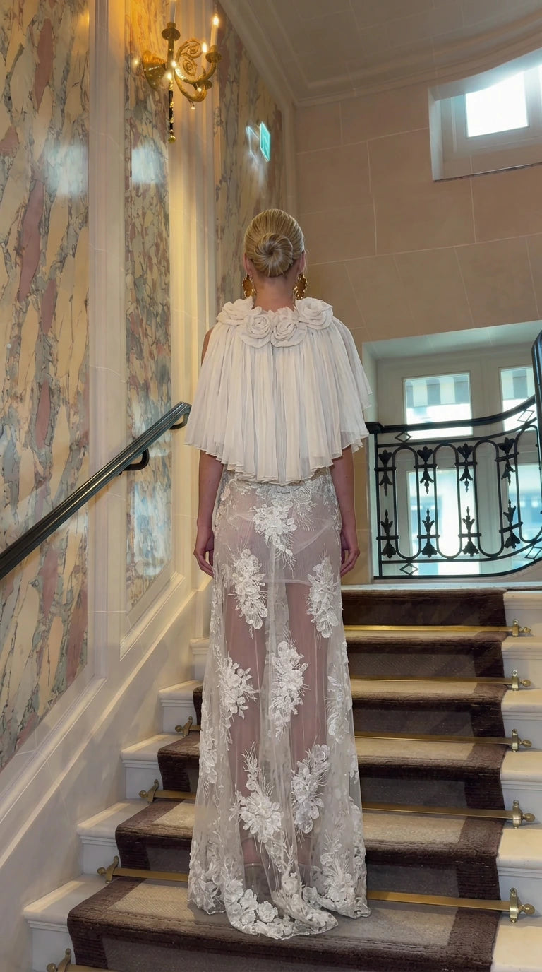 Back view of Ivory embroidered evening gown showing pleated capelet details