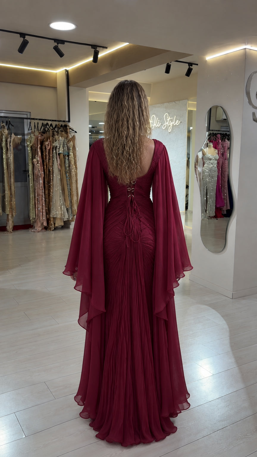 Back view of burgundy maxi gown showing open lace-up corset detail and cape sleeves