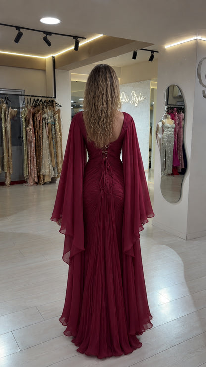 Back view of burgundy maxi gown showing open lace-up corset detail and cape sleeves