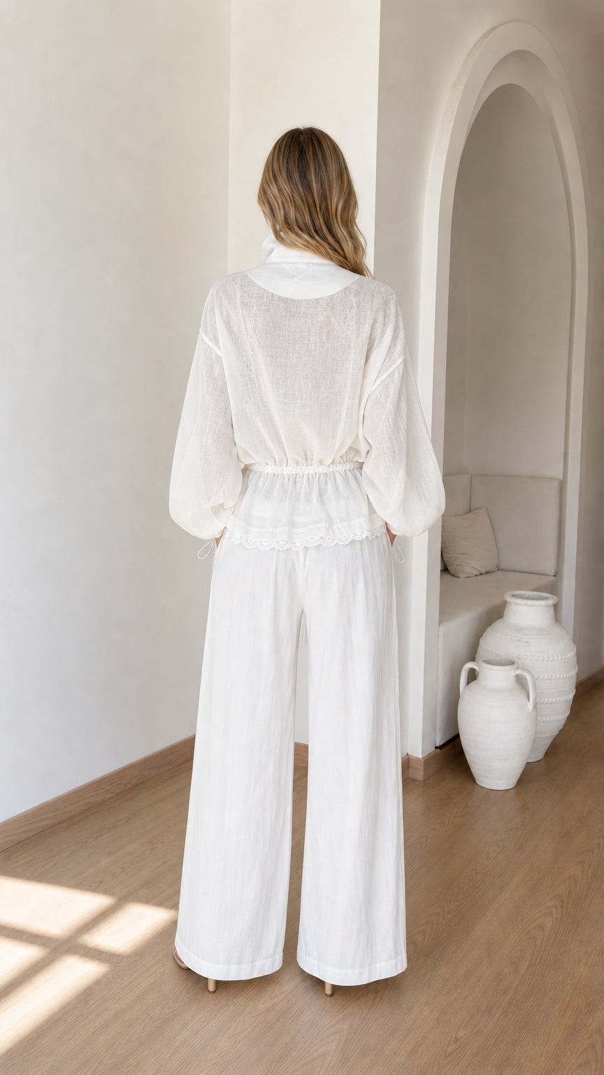 Back view of woman wearing white zip-up jacket and matching wide-leg trousers
