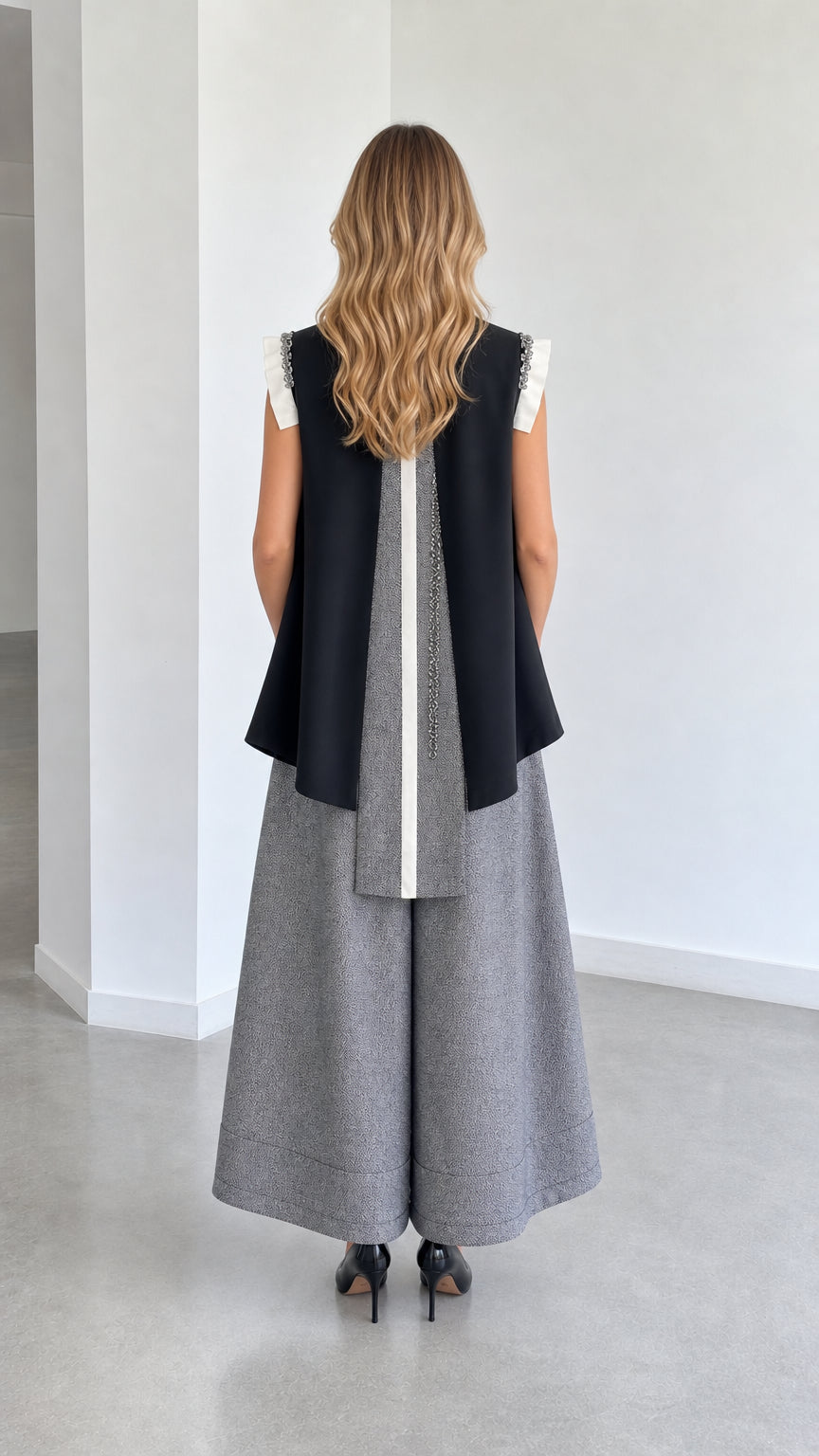 Back view of model in black color-block sleeveless vest and wide-leg pants