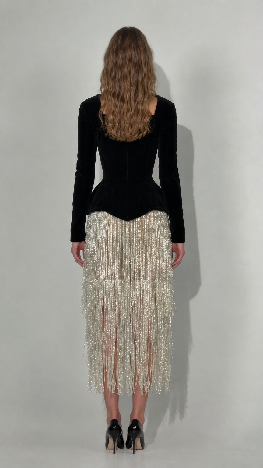 Back view of black long sleeve velvet corset dress with fringe midi skirt