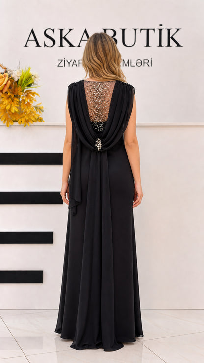 Back view of black evening gown featuring beaded sheer illusion back and crystal brooch