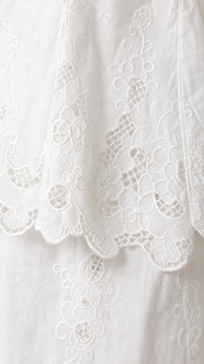 Close-up detail of the white floral eyelet embroidery and scalloped lace hemline