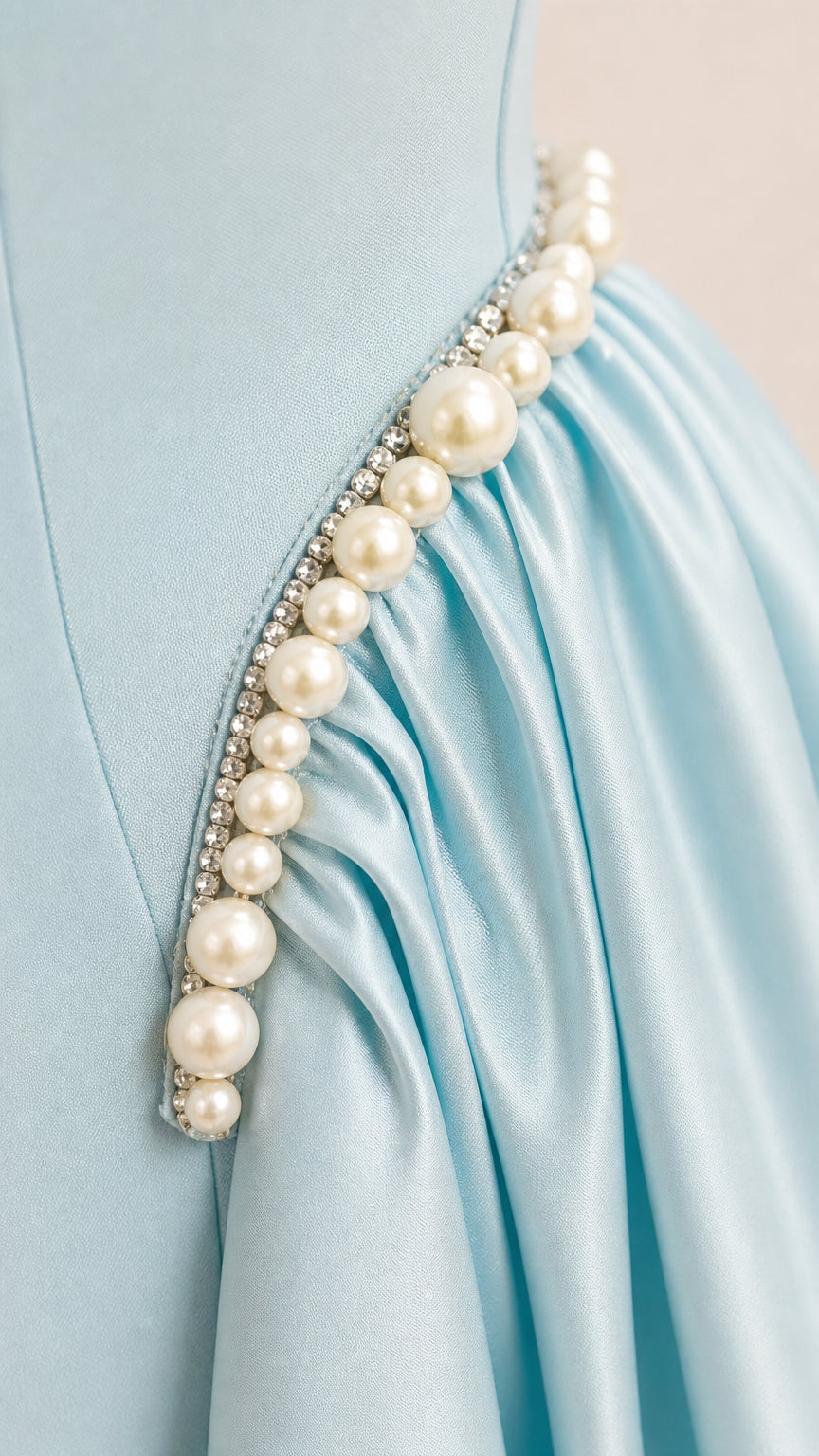 Close-up detail of pearl and crystal trim with ruched pleats on satin fabric