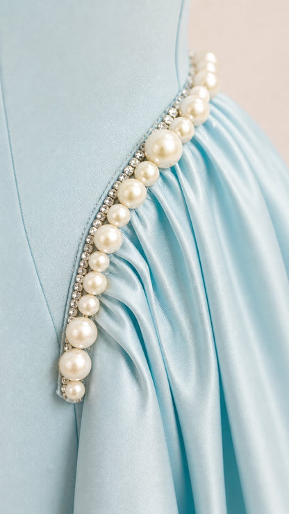 Close-up detail of pearl and crystal trim with ruched pleats on satin fabric