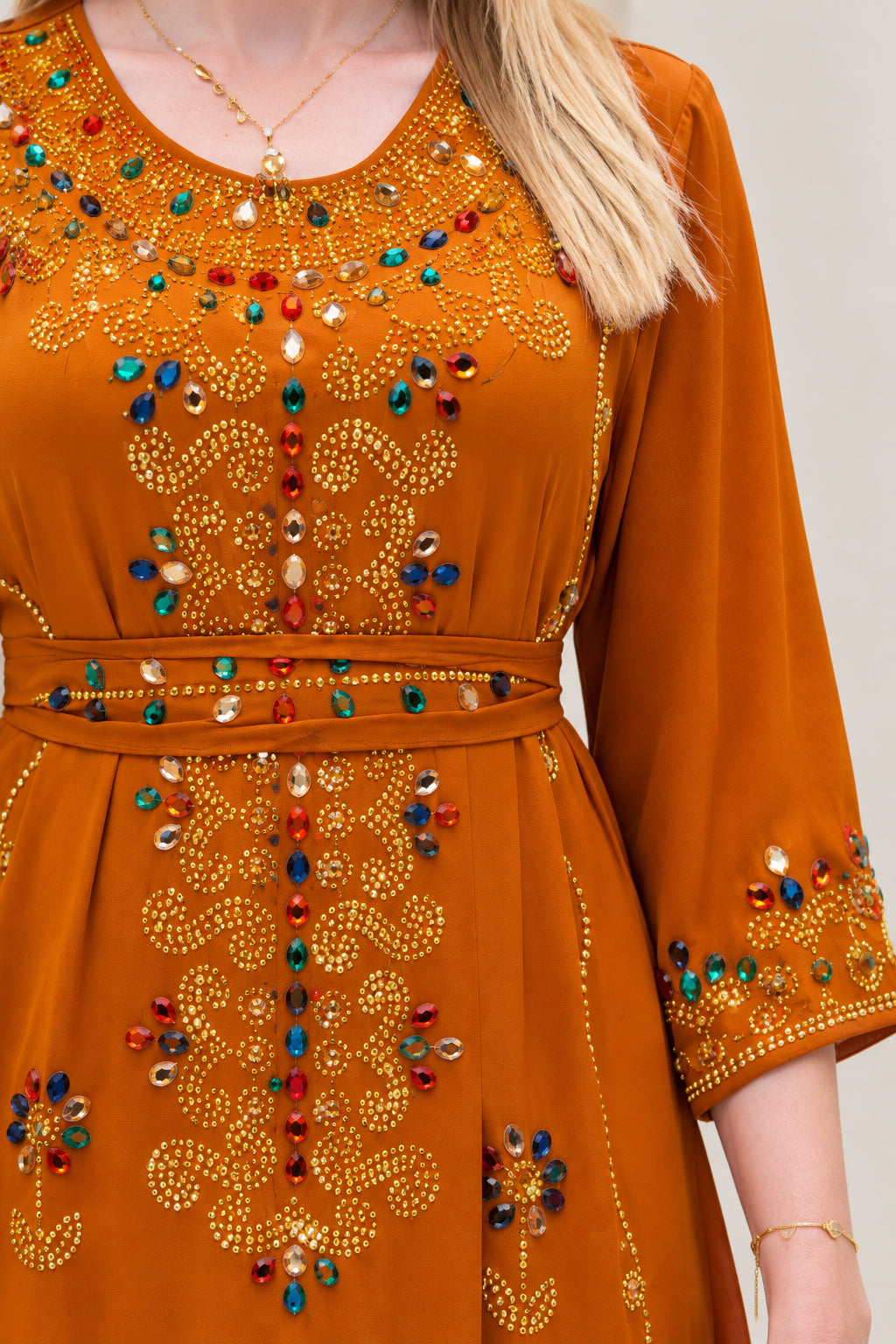 Close-up of intricate rhinestone and bead embellishments on rust orange kaftan bodice