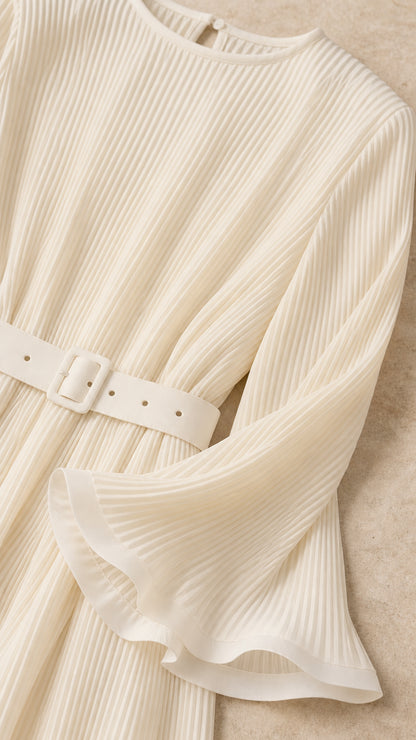 Close-up detail of cream accordion pleated fabric, matching belt buckle, and flared cuff