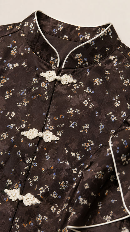Close-up of Mandarin collar, white piping, and frog closures on dark brown floral fabric