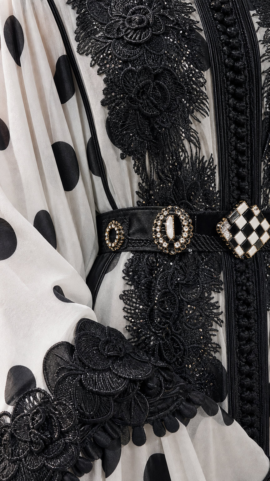 Close-up detail of ornate black lace trim, neckline embroidery, and jeweled belt buckle